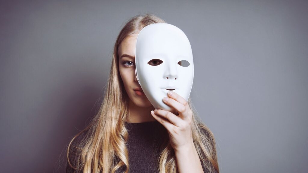 Teen holding a mask to represent emotional numbness linked to Adderall use