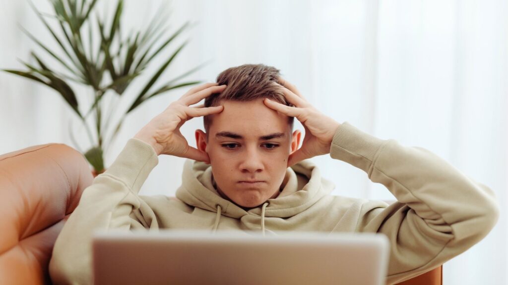 Teen showing stress and anxiety while using a laptop at home