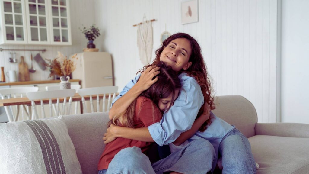 Parent comforting teen on couch during emotional conversation about substance use